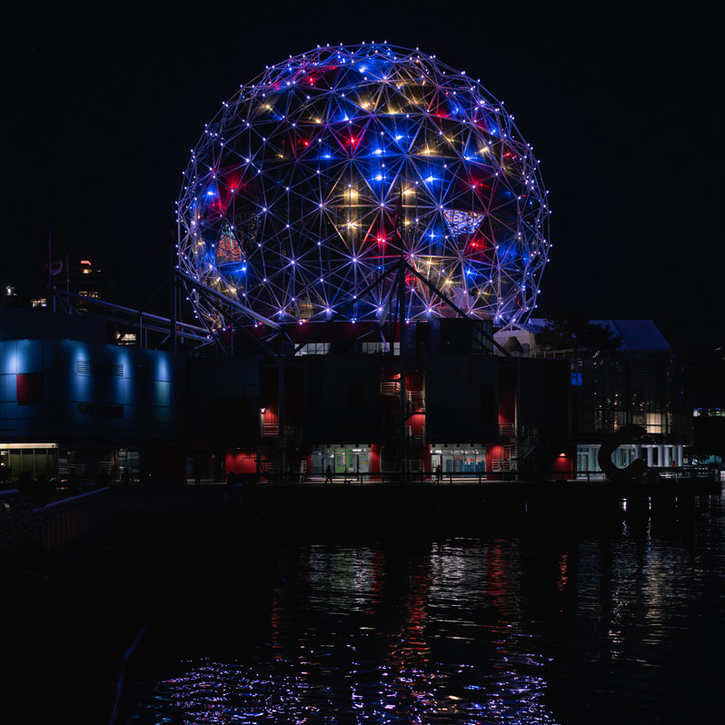 The science world lights and reflection in the water of false creek at night