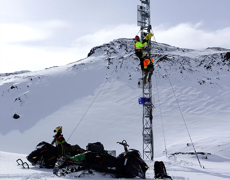 A worker supervises two Rope Technicians practicing tower rescue in the snowy mountians on a Communications tower